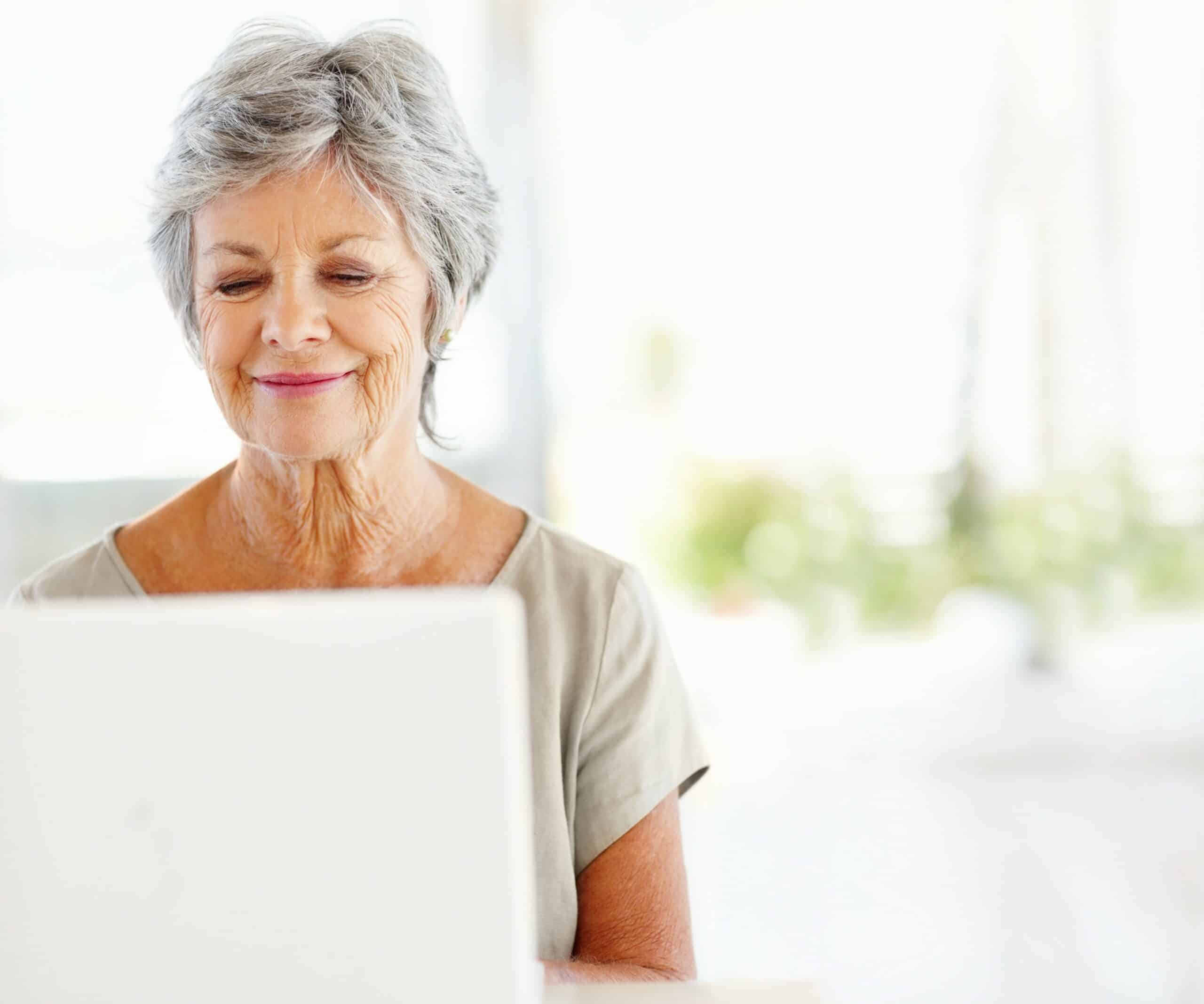 Happy mature woman using a laptop at home